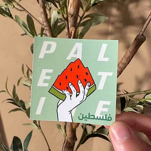 a person holding a sticker of watermelon with the olive tree as a background