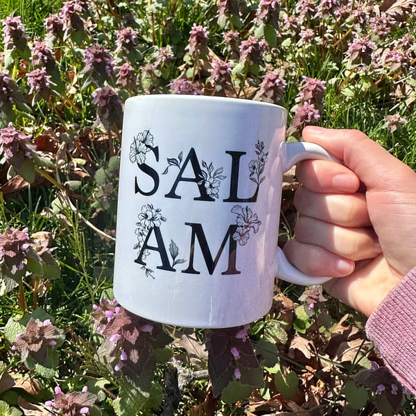 A person holding Salam mug with the background of flowers